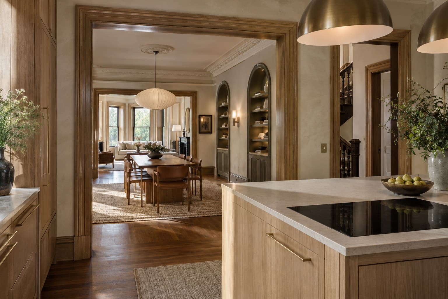 View from a white oak kitchen through a wide cased opening into a dining room with arched built-in shelving
