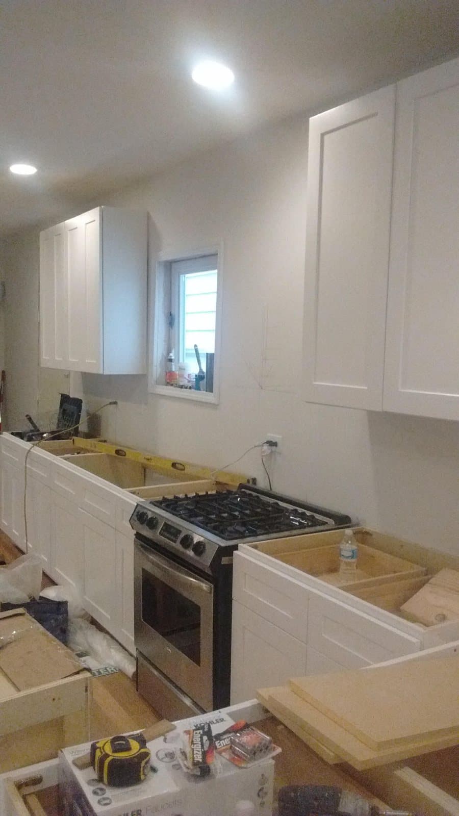 White Shaker cabinets installed along a long wall with the range in place and no countertops yet, waiting for the template