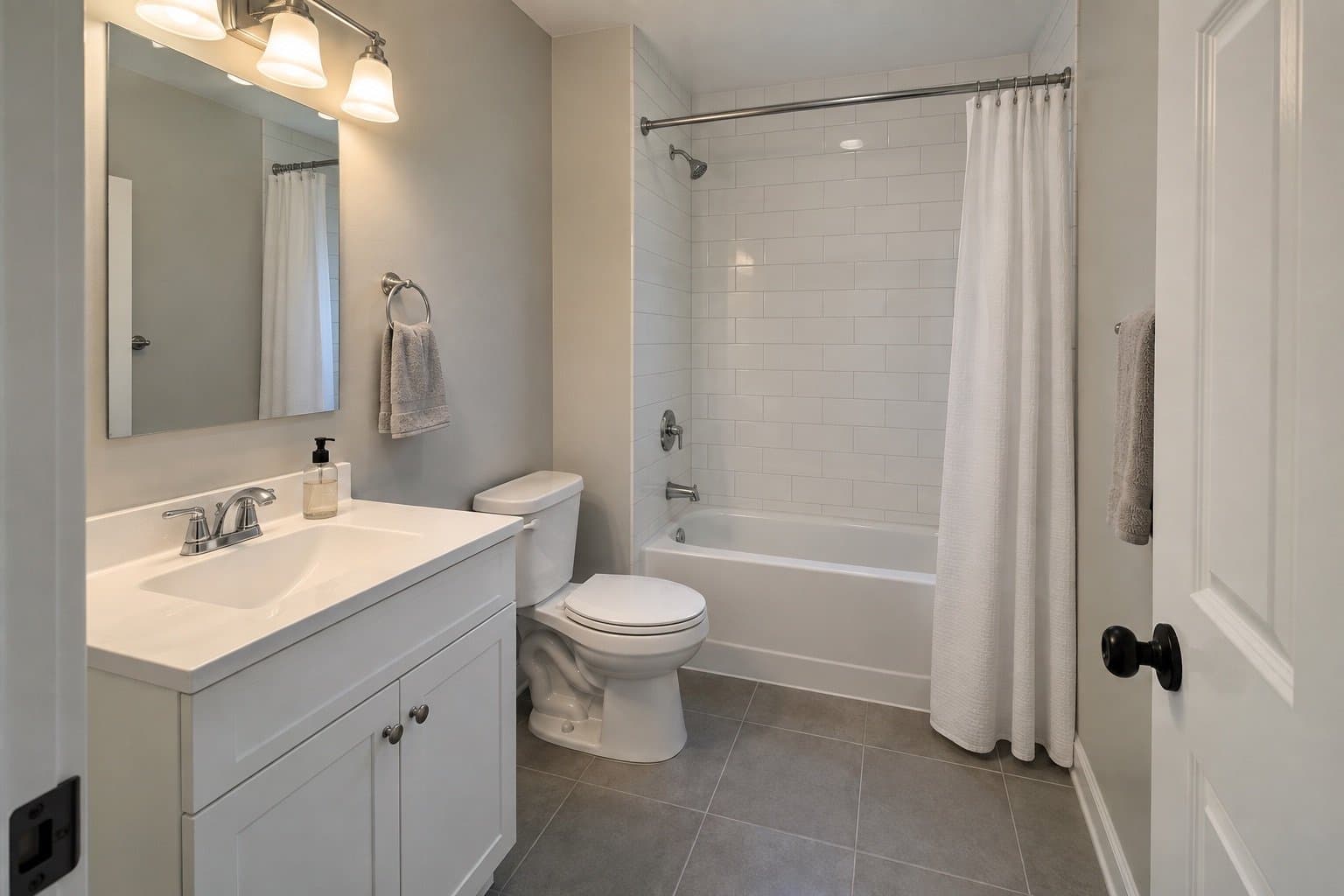 Bathroom with a white shaker vanity, a tub shower in white subway tile with a curtain, and large grey floor tile