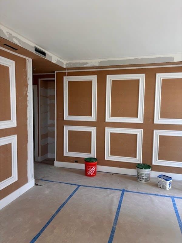 Muro con marcos de moldura de panel imprimados y zoclo instalados sobre tablaroca, listo para pintar